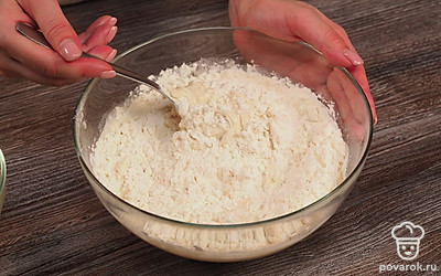 Приступите к приготовлению теста для турецкой лепешки. Для этого налейте воду в глубокую миску, добавьте соль и перемешайте до растворения. Влейте растительное масло. Введите муку частями, постоянно помешивая. Когда оно станет более оформленным, замесите его. Накройте пищевой пленкой и уберите в холодильник на полчаса.