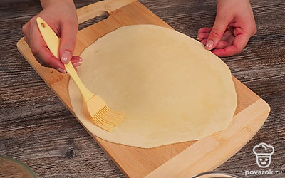 Сделайте основу для лепешек гезлеме. Достаньте тесто и еще раз вымесите его на протяжении минуты. Разделите на несколько одинаковых частей и сформируйте шарики. Возьмите скалку и раскатайте небольшие лепешки. Смажьте их с двух сторон растительным маслом и выложите друг на друга. Оставьте отдыхать на 10 минут.