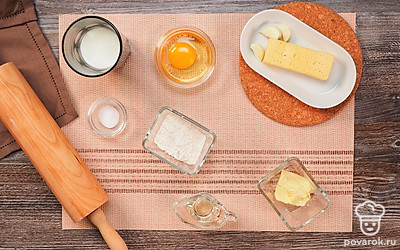 Подготовьте сковороду (желательно с антипригарным покрытием). Подготовьте глубокую посуду для теста, скалку. Выложите все ингредиенты на видное место. Натрите сыр на средней терке, измельчите чеснок.