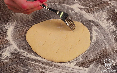 Продолжайте готовить сырные лепешки на молоке. Разделите тесто на 8 одинаковых кусочков. Руками скатайте шарики. Выложите их на стол, присыпанный мукой. Возьмите скалку и раскатайте лепешки. Толщина должна быть примерно 5 мм. Возьмите вилку и проткните лепешку в нескольких местах. Благодаря этому они не вздуются в процессе обжаривания на сковороде.