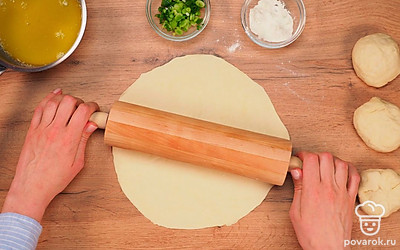 Сформируйте 4 шара из теста. Для этого разделите его на 4 одинаковые части и каждую скатайте в колобок. Возьмите скалку, припылите ее мукой и раскатайте шары очень тонко.