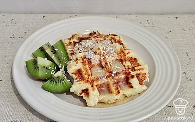 Подавайте вафли к столу сразу после приготовления. Перед подачей украсьте кокосовой стружкой. Полейте сгущенкой и дополните любыми фруктами. 