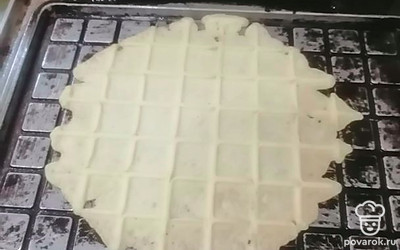 Я готовлю в электровафельнице. Она моя ровесница, но печет идеально. Выложите на середину разогретой вафельницы одну столовую ложку теста. Выпекайте до готовности. Ножом снимите вафельный блин и сразу сверните в плотный рулетик. Остывшая вафля станет хрупкой, при заворачивании будет ломаться и сыпаться. Я разрезаю получившуюся вафлю пополам. 