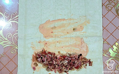 Поджаренный бекон нарежьте небольшими кусочками, выложите на лаваш. Полейте сверху сметанно-томатным соусом. 