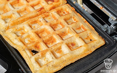 Смажьте сливочным маслом дно формы вафельницы. Выложите нужное количество теста на разогретую поверхность. Выпекайте вафли до золотистой корочки.