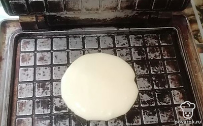 Электровафельницу немного разогреваем. Выливаем одну столовую ложку теста и выпекаем до готовности.