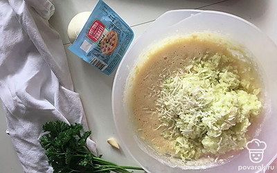 Добавьте к яйцам натертый на терке сыр (50 граммов) с 1 долькой чеснока, муку, соду, отжатый от лишней влаги кабачок, немного зелени. Перемешайте до однородности.