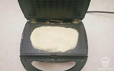 Возьмите электровафельницу, промажьте ее растительным маслом, выложите на нее столовую ложку приготовленного теста и выпекайте вафлю в течение 2 минут до легкой золотистости. Повторяйте аналогичные шаги со всем тестом. В чистой посуде соедините два вида сгущенного молока и используйте смесь в качестве начинки между двумя вафлями.