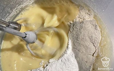 Добавьте растопленное сливочное масло, продолжая взбивать, влейте молоко и постепенно введите просеянную муку и разрыхлитель.