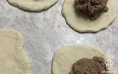 Раскатайте колобки в тонкие лепешки, выложите на середину лепешки начинку (по столовой ложке с горкой).