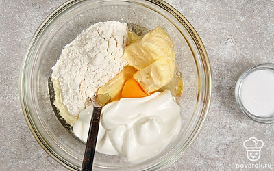 В другой миске смешайте муку со сметаной, куриным яйцом, сливочным маслом и солью. Замесите густое однородное тесто.