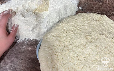 Тесто подошло. Достаем его из кастрюли и выкладываем на стол, где предварительно рассыпали муку.