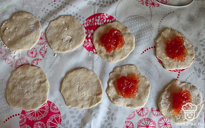 После того, как тесто поднялось, можно приступать к приготовлению пирогов. Раскатываем небольшие круги и добавляем ложку повидла. Скрепляем две половины теста по краям. 