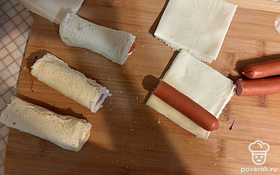 Сделайте заготовки. Заверните в хлеб сыр с сосиской. 