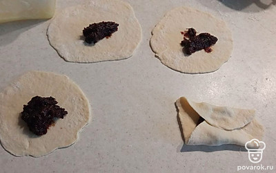 Чернослив пропускаем через мясорубку и смешиваем с сахаром. Выкладывпем в центр начинку, формируем конверты.