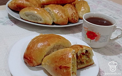Пышные дрожжевые пирожки с капустой, морковью и луком в духовке выложите на красивое блюдо и подавайте к столу в теплом виде в сочетании с любимым напитком.