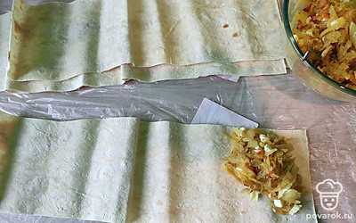 Разрежьте лаваш на широкие полоски. Выложите начинку в виде треугольника и начните скручивать по направлению к другому концу наискосок. 