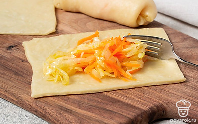 Приготовьте трубочки. Разделите тесто на несколько частей, раскатайте их на небольшие прямоугольники. Полученную начинку разложите на край заготовки. Подверните края, а потом сверните в трубочки. Выложите изделия на противень, поставьте их в духовку и выпекайте 20 минут.