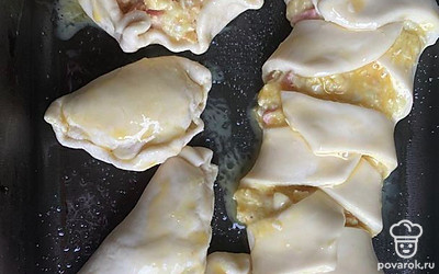 В каждый прямоугольник положите начинку, отправьте пирожки на противень, смажьте яйцом. Запекайте в духовке в течение 15 минут.
