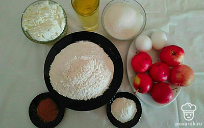Яйца разделите на желтки и белки. Желтки слегка взбейте вилкой. Муку просейте и смешайте с разрыхлителем. Яблоки помойте. Противень застелите пергаментной бумагой и смажьте растительным маслом.