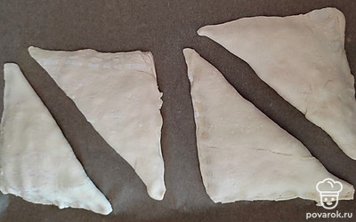 Выложите 1-2 ложки сырной начинки на половинку квадрата теста, сверните треугольник и по краям немного примните пальцами, соединяя края.