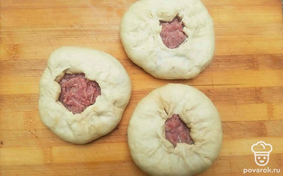 Подошедшее тесто разделите на 10 частей и скатайте их в шарики. На смазанной маслом доске раскатайте каждый шарик в круглый пласт, выложите посередине начинку с отступом 1 сантиметр от края. Края пласта соберите в гармошку, оставляя посередине небольшое круглое отверстие. Каждый беляш немного придавите.