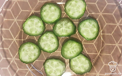 Огурец помойте и нарежьте кружочками. Выложите на тарелку. 