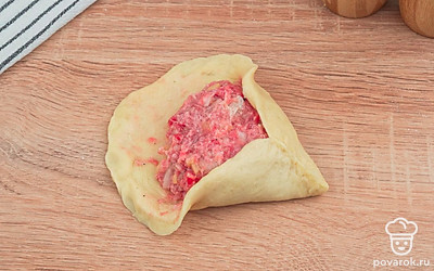 Из каждого такого кусочка раскатайте кружок, в центр выложите начинку и начинайте защипывать края, формируя треугольник и оставляя отверстие в центре.