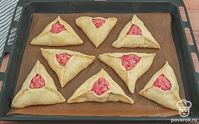 Противень застелите пергаментной бумагой, выложите получившиеся треугольнички, смажьте тесто взбитым куриным яйцом и отправляйте в заранее разогретую до 200 градусов духовку на 5 минут. Затем убавьте температуру до 170 градусов и продолжайте выпекать еще 25 минут.