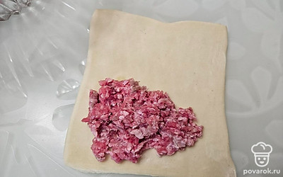 Тесто раскатайте с помощью скалки. Разрежьте на четыре одинаковых части. Выложите фарш на край теста, равномерно распределите. 