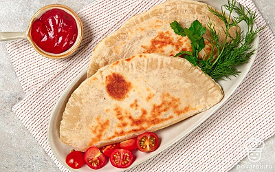 Выложите чебуреки на большую тарелку. Рядом поставьте пиалу с кетчупом или любым другим соусом. Подайте блюдо на стол.
