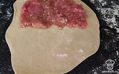 Положите фарш на половину теста. Фарш я делаю сама, и сразу проворачиваю мясо вместе с луком. Если используете готовый фарш, добавьте в него мелко порезанный лук. 