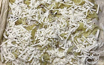 Расстелите второй лаваш, выложите картофель и посыпьте его тертым сыром.