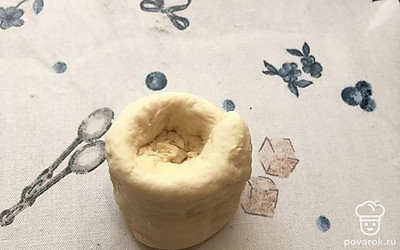 Пласт смазываем растительным маслом и сворачиваем в рулет по принципу слоеного теста. Переворачиваем рулет ножкой, сверху делаем углубление. Засыпаем ложкой начинку и закрываем булочку, приплющивая тесто.