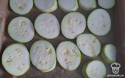 Кабачок помойте, просушите и нарежьте кружочками. Выложите его на противень, застеленный пергаментом. Запекайте в духовке 25 минут при 180 градусах.