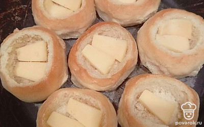 Твердый сыр нарежьте под размер отверстия в булочке. В каждую булочку положите кусочек сыра. Булочки выложите в форму для запекания.