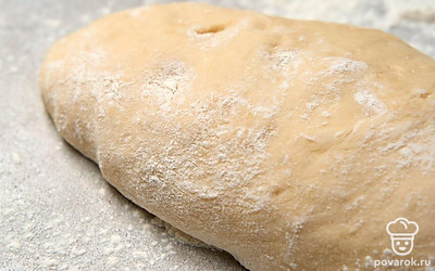 Присыпьте рабочую поверхность отложенной мукой. Обомните поднявшееся тесто и переложите его на рабочую поверхность.