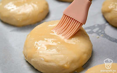 Еще раз слегка прижмите верхушки заготовок. Промажьте их с помощью силиконовой кисточки смесью яичного желтка с оставшимся молоком.