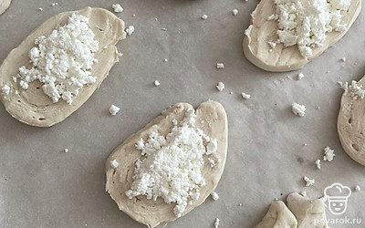 Выложите их на пергаментную бумагу. Сверху выложите творог.