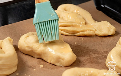 Смешайте куриное яйцо с молоком. Смажьте плюшки. Отправьте противень в духовку на 12 минут. Через 8 минут снизьте температуру до 170 градусов.