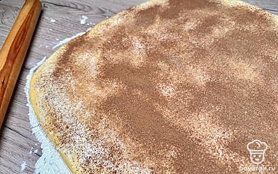 Смажьте сливочным маслом, посыпьте тростниковым сахаром, а затем специями (равномерно). Сверните тесто в плотный рулет. 