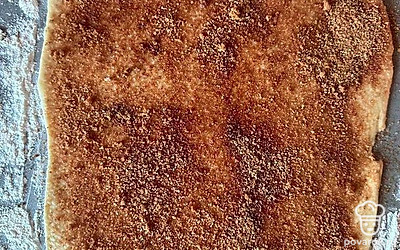 Делаем посыпку: смешиваем сахар с корицей. На раскатанное тесто кладем немного масла растопленного и посыпаем корицей.