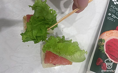 Возьмите лист салата-латука и шпажки. Соедините с ломтиками хлеба. 