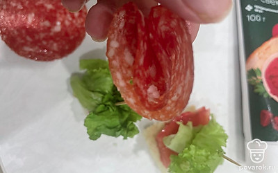 Ломтик салями сложите в четыре раза и насадите на шпажку в самом конце.