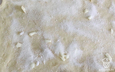 Тесто смазать маслом, посыпать сахаром, скатать в рулет.