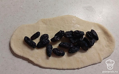 Готовое тесто раскатать. Выложить изюм.
