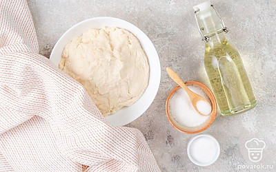 Налейте в миску теплую воду. Добавьте 2 ст.л. сахара и дрожжи, перемешайте. Накройте смесь и оставьте ее на 15 минут. После этого добавьте к дрожжам соль и немного муки. Начните замешивать тесто, постепенно добавляя всю муку. В конце добавьте 2 ст.л. масла и еще раз немного вымесите тесто. После этого накройте его полотенцем и оставьте на 40 минут.