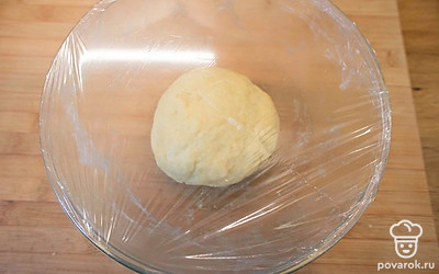 Замесите гладкое, упругое и не липнущее к рукам тесто: сначала лопаткой, а потом руками. При необходимости, добавьте немного теплого молока, чтобы легче было собрать тесто в шар. Если во время вымешивания теста у вас какие-то кусочки прилипают к доске, не старайтесь их вмешать в тесто, чтобы потом в нем не встречались уплотнения. Переложите тесто в чашу, смажьте ее растительным маслом, закройте ее пищевой пленкой и отправьте в теплое место на 2 часа на расстойку. За это время тесто увеличится в 2-2,5 раза.