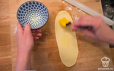 Растопите в микроволновке 10 грамм сливочного масла. Каждый шарик теста раскатайте в длинный пласт, толщиной 5-6 миллиметров. Смажьте его сливочным маслом.