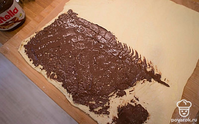 Поделите пласт теста пополам и на одну половину намажьте шоколадную пасту. Не делайте очень толстый слой, но и просветов быть не должно. Накройте второй половиной сверху.